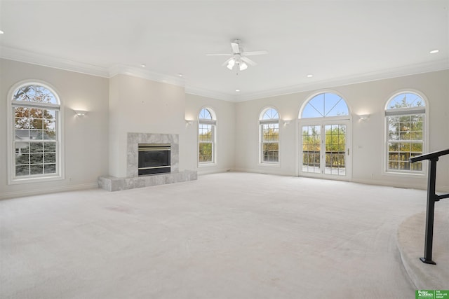 unfurnished living room with a fireplace, light colored carpet, ceiling fan, and crown molding