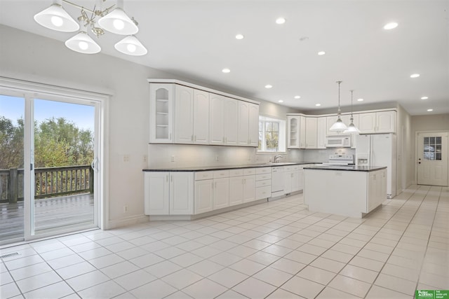 kitchen featuring white appliances, light tile patterned floors, tasteful backsplash, decorative light fixtures, and white cabinetry