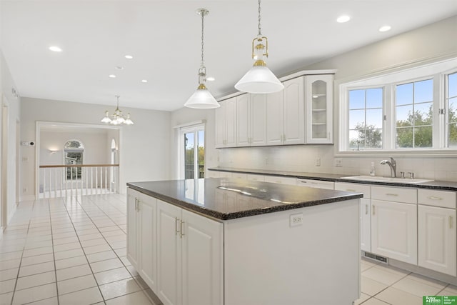 kitchen featuring tasteful backsplash, white cabinetry, sink, and a center island