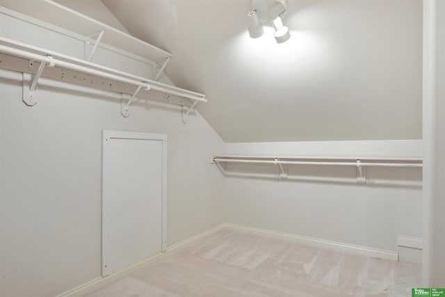 walk in closet featuring light colored carpet and lofted ceiling