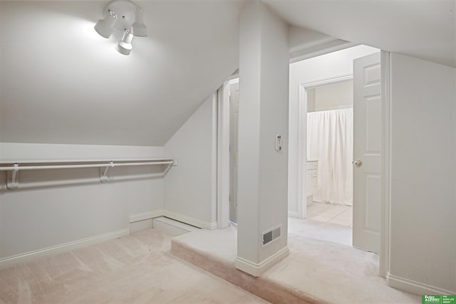 spacious closet with light carpet and vaulted ceiling