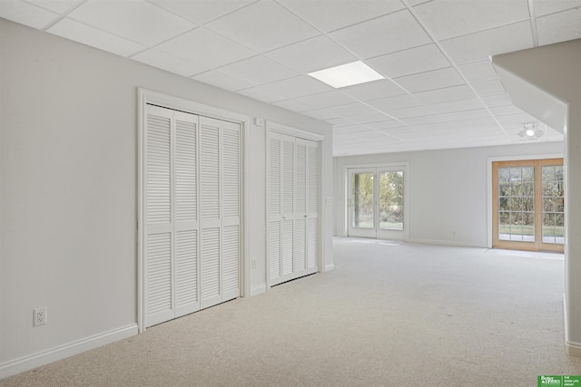 interior space with carpet flooring, a drop ceiling, and two closets