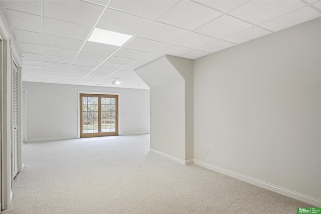 spare room featuring a paneled ceiling and light carpet