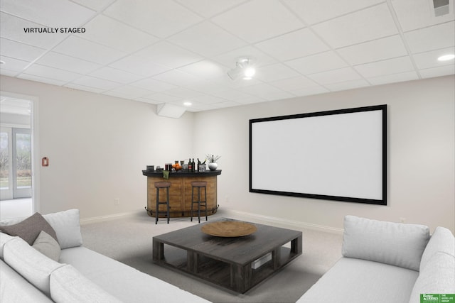 carpeted cinema room with a drop ceiling