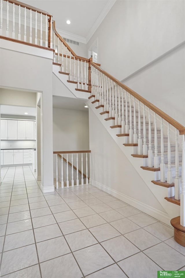 stairway with tile patterned floors and crown molding