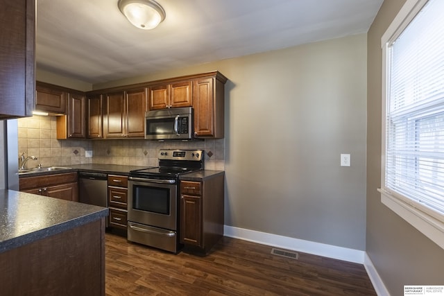 kitchen with dark wood-type flooring, appliances with stainless steel finishes, backsplash, and sink