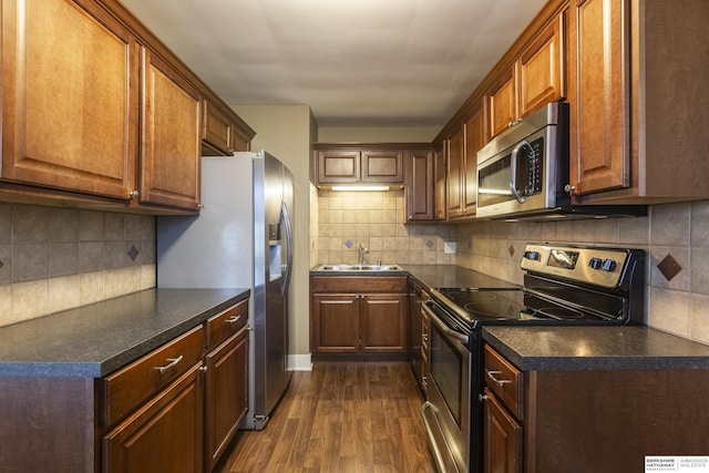 kitchen featuring appliances with stainless steel finishes, dark hardwood / wood-style floors, decorative backsplash, and sink