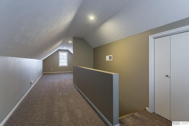 additional living space with a textured ceiling, lofted ceiling, and dark carpet