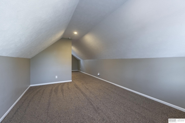 additional living space with a textured ceiling, vaulted ceiling, and carpet flooring