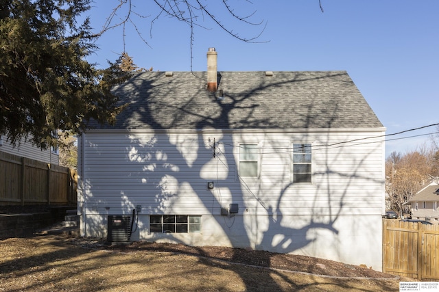 rear view of house with cooling unit and a lawn