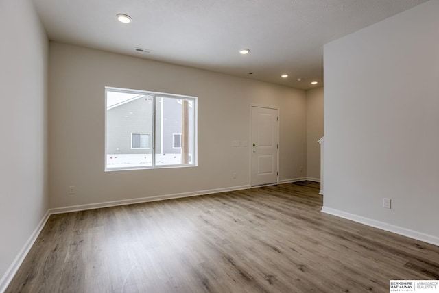 spare room featuring recessed lighting, visible vents, baseboards, and wood finished floors