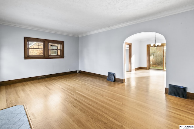 empty room with a chandelier, a wealth of natural light, and ornamental molding