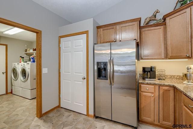 kitchen with stainless steel refrigerator with ice dispenser, light stone countertops, and washing machine and clothes dryer