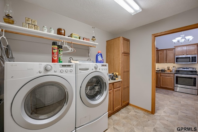 laundry room with a textured ceiling, cabinets, a chandelier, and washer and clothes dryer