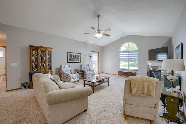 carpeted living room with ceiling fan and vaulted ceiling