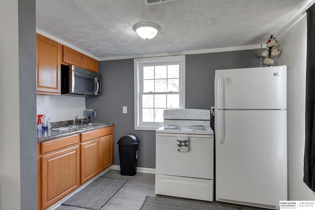 kitchen featuring white appliances, a textured ceiling, and sink