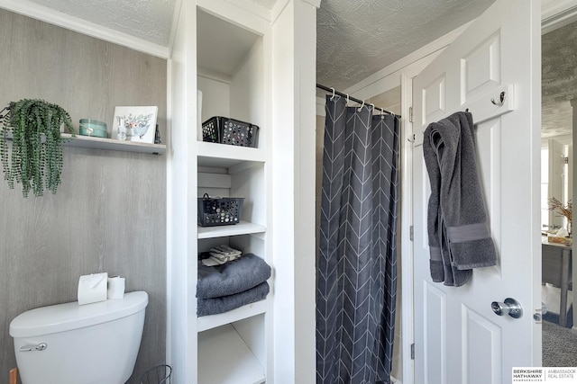 bathroom featuring toilet, built in shelves, a textured ceiling, and a shower with shower curtain