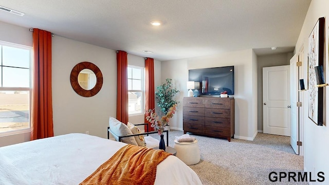 bedroom featuring light colored carpet and a textured ceiling