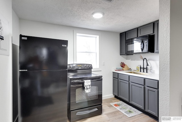 kitchen featuring gray cabinets, black appliances, light wood-type flooring, a textured ceiling, and sink