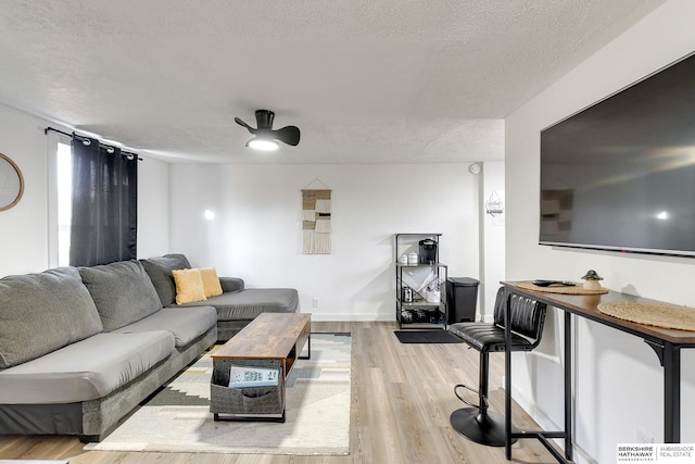 living room featuring a textured ceiling, ceiling fan, and light wood-type flooring