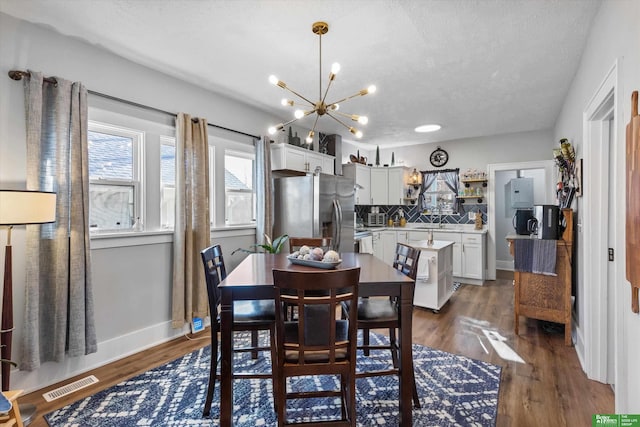 dining area with dark hardwood / wood-style flooring, a textured ceiling, and a chandelier