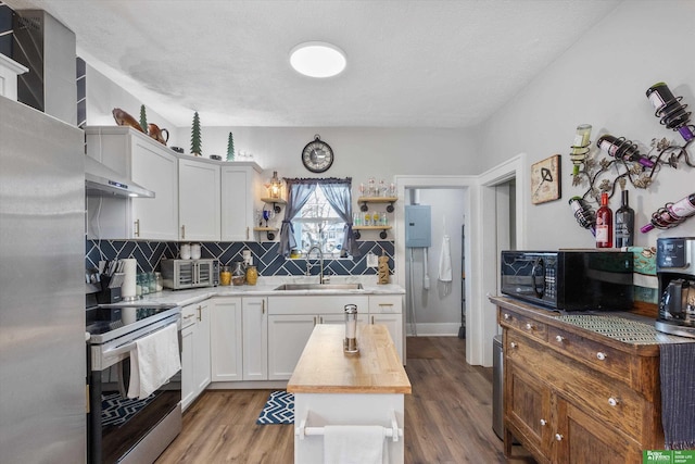 kitchen featuring stainless steel appliances, sink, butcher block counters, white cabinetry, and hardwood / wood-style flooring