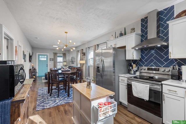 kitchen with butcher block counters, white cabinets, a center island, wall chimney exhaust hood, and appliances with stainless steel finishes