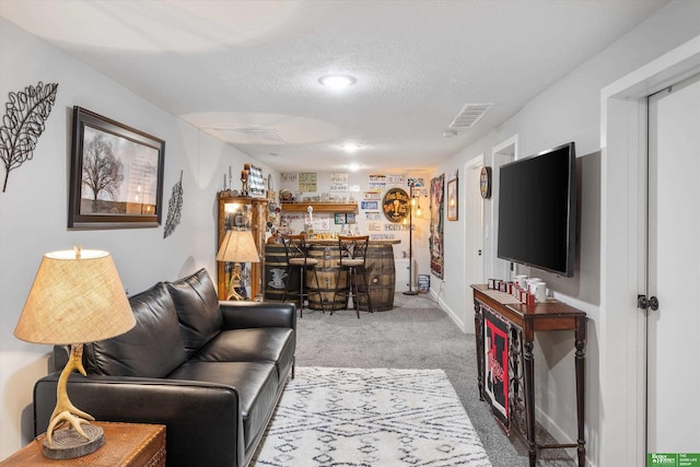 living room featuring bar area, a textured ceiling, and carpet flooring