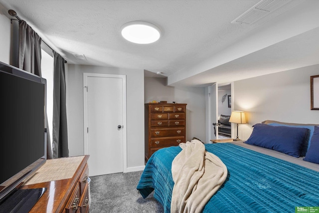 bedroom with a textured ceiling and dark colored carpet