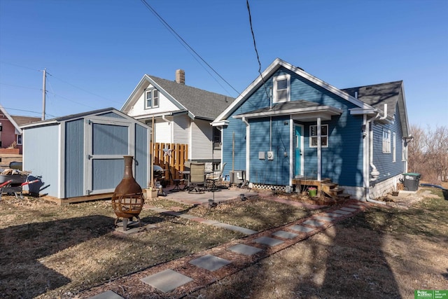 rear view of house featuring a fire pit, a patio area, and a shed