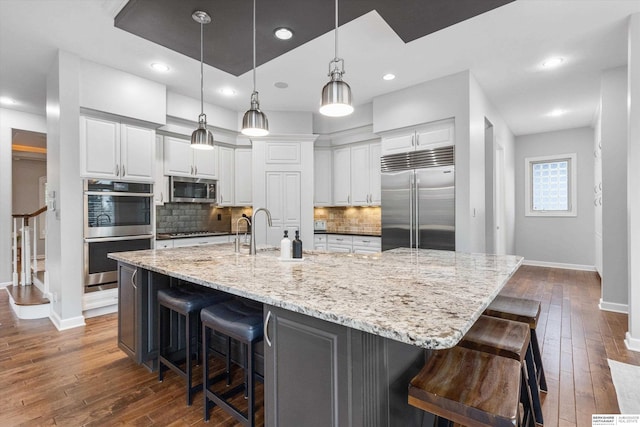 kitchen with pendant lighting, a breakfast bar, a large island, white cabinetry, and stainless steel appliances