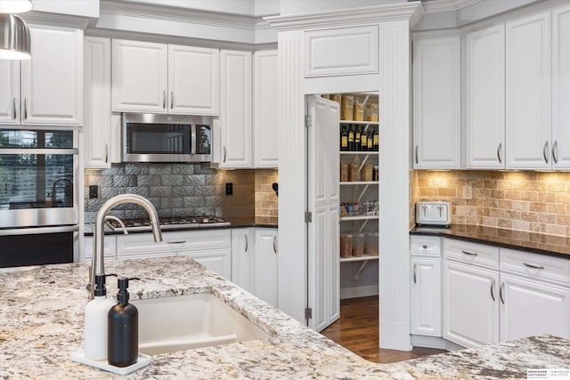 kitchen with white cabinets, dark stone countertops, sink, and stainless steel appliances