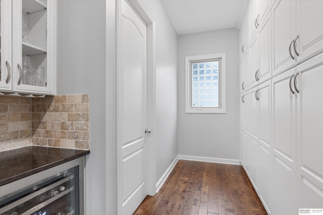 bar with white cabinets, backsplash, beverage cooler, and dark wood-type flooring