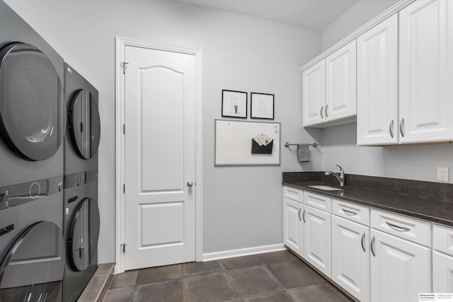 washroom with stacked washer / drying machine, cabinets, and sink