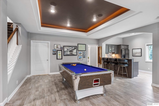 recreation room with wood-type flooring, a tray ceiling, bar, and billiards