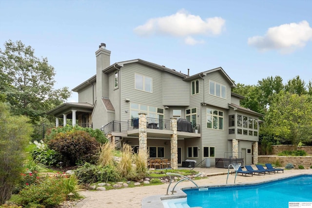 back of house with a balcony, a fenced in pool, and a patio