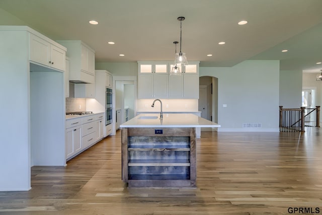 kitchen featuring white cabinets, an island with sink, decorative light fixtures, and appliances with stainless steel finishes