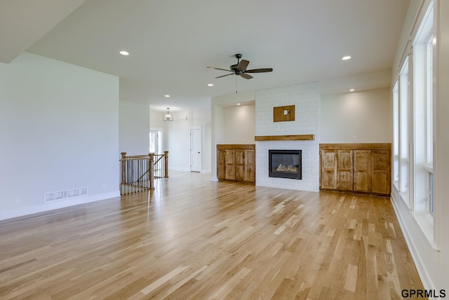 unfurnished living room featuring ceiling fan, a fireplace, and light hardwood / wood-style floors