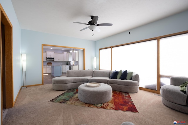 living room featuring light colored carpet and ceiling fan with notable chandelier