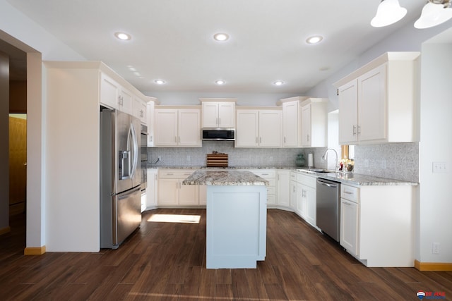 kitchen with a kitchen island, light stone countertops, white cabinetry, and appliances with stainless steel finishes