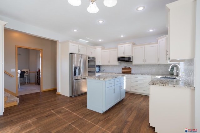 kitchen with white cabinetry, a center island, sink, stainless steel appliances, and tasteful backsplash