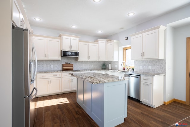 kitchen featuring appliances with stainless steel finishes, white cabinetry, a kitchen island, and dark wood-type flooring