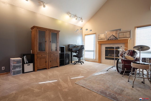 carpeted office featuring a fireplace, rail lighting, and high vaulted ceiling