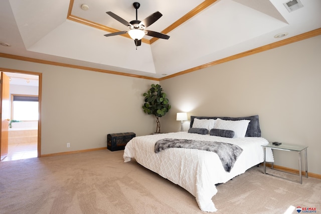 carpeted bedroom featuring a tray ceiling, ensuite bath, ceiling fan, and crown molding