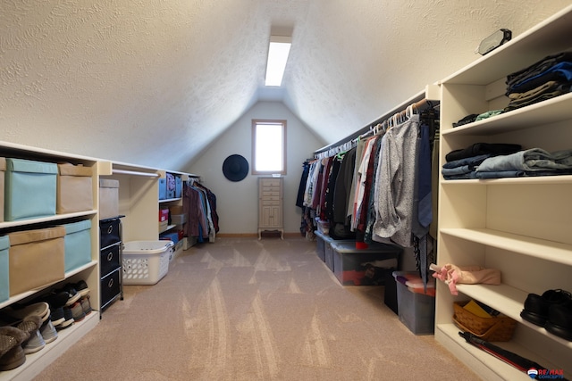 spacious closet with light colored carpet and vaulted ceiling