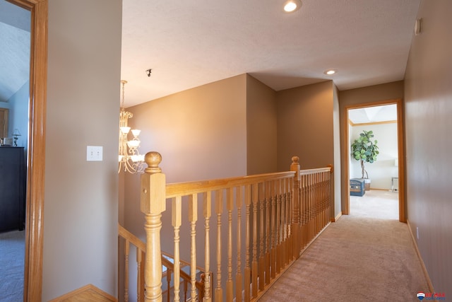 corridor featuring a textured ceiling, carpet floors, and a notable chandelier