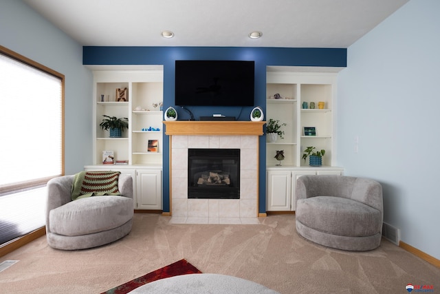 living room with a tile fireplace, light carpet, and a wealth of natural light