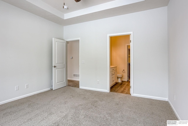 unfurnished bedroom featuring light carpet, connected bathroom, and ceiling fan