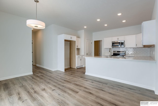 kitchen featuring white cabinets, pendant lighting, stainless steel appliances, and decorative backsplash