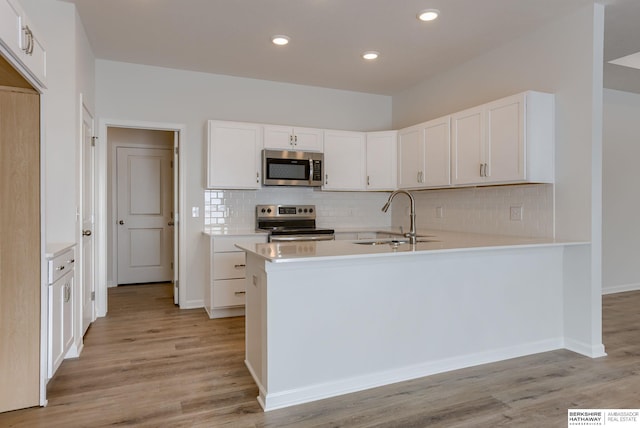 kitchen with white cabinets, kitchen peninsula, sink, and appliances with stainless steel finishes